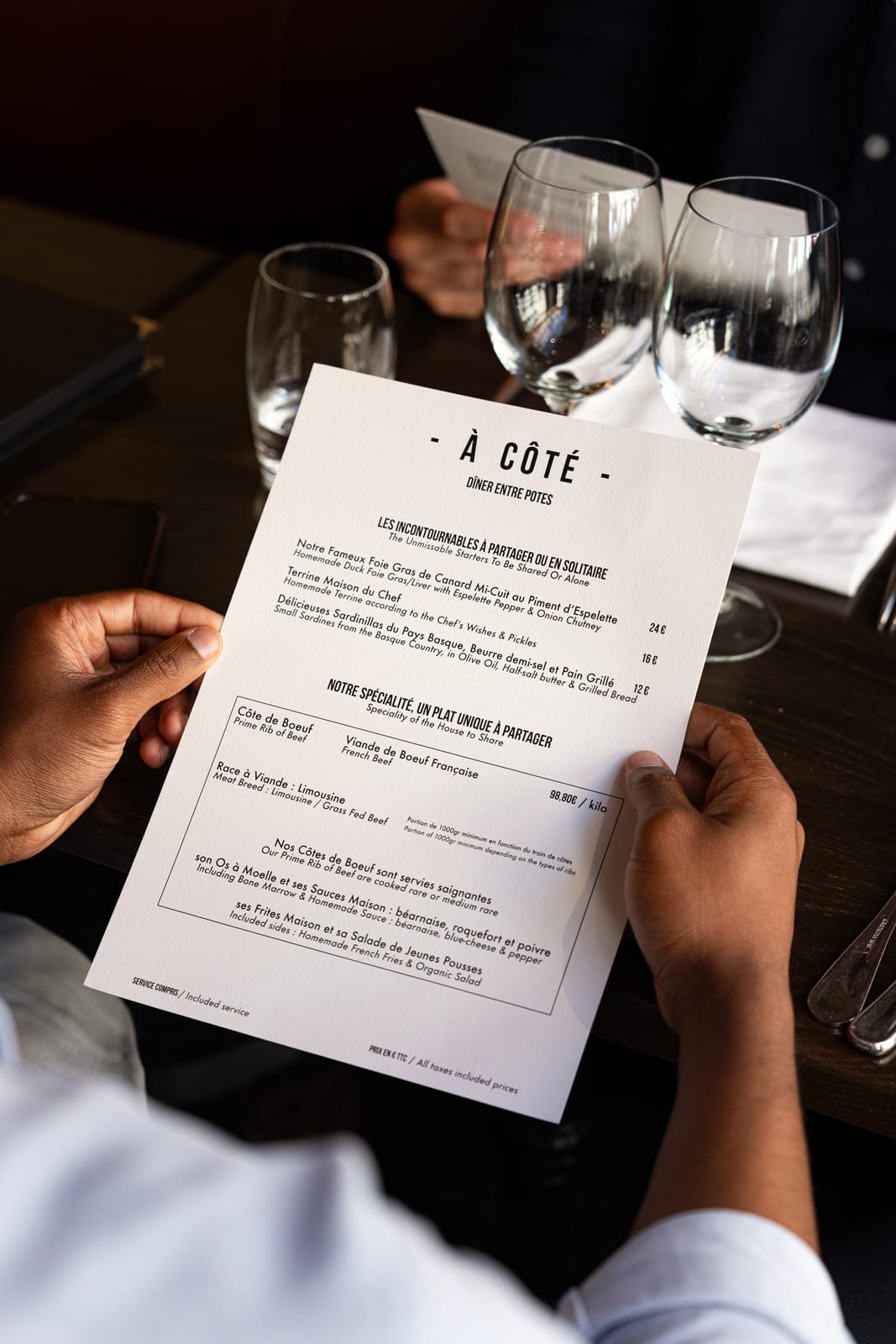 Un ospite consulta il menu di À Côté, con la costata francese di razza Limousine da condividere