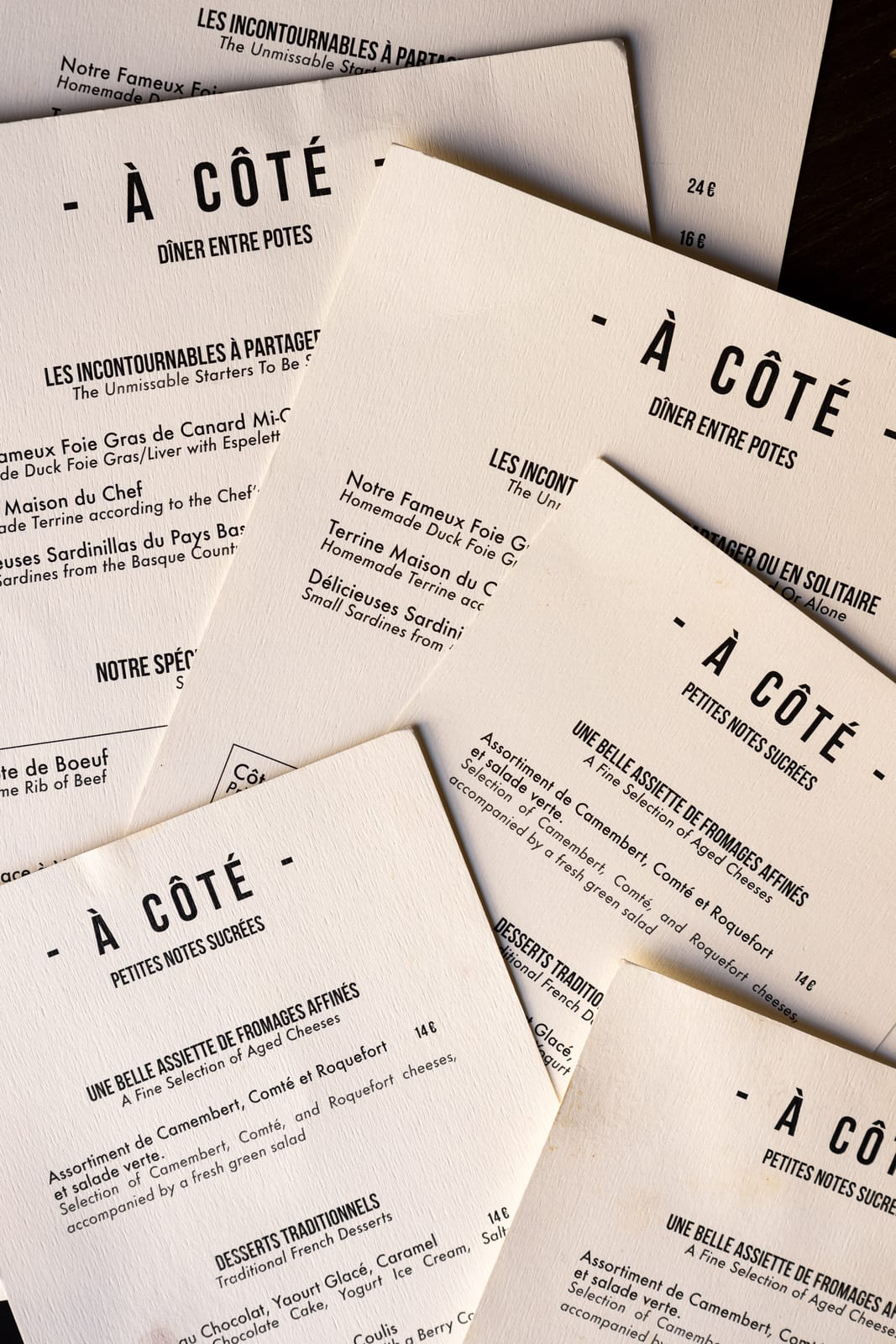 À Côté menus fanned out, written in French and English: starters to share, côte de bœuf and desserts